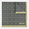 View 2 of product The Turnbull & Asser UK Geometric Yellow Tile Pocket Square in Silk features a sophisticated geometric square pattern in gold and navy, accented with subtle concentric squares and a discreet label stitched into the bottom right corner. Its double-sided design is highlighted by a folded corner that reveals a contrasting dotted navy and white underside.