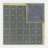 View 4 of product The Turnbull & Asser UK Geometric Yellow Tile Pocket Square in Silk features a sophisticated geometric square pattern in gold and navy, accented with subtle concentric squares and a discreet label stitched into the bottom right corner. Its double-sided design is highlighted by a folded corner that reveals a contrasting dotted navy and white underside.