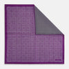View 1 of product The Turnbull & Asser UK Geometric Purple Tile Pocket Square in Silk features a vibrant purple hue adorned with concentric square motifs. One corner is folded to reveal its double-sided design, showcasing a contrasting black-and-white dotted underside.