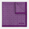 View 2 of product The Turnbull & Asser UK Geometric Purple Tile Pocket Square in Silk features a vibrant purple hue adorned with concentric square motifs. One corner is folded to reveal its double-sided design, showcasing a contrasting black-and-white dotted underside.