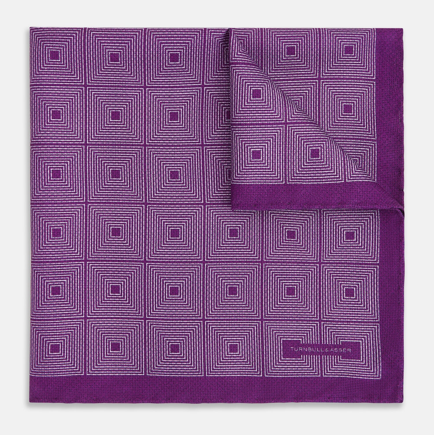 View 2 of product The Turnbull & Asser UK Geometric Purple Tile Pocket Square in Silk features a vibrant purple hue adorned with concentric square motifs. One corner is folded to reveal its double-sided design, showcasing a contrasting black-and-white dotted underside.
