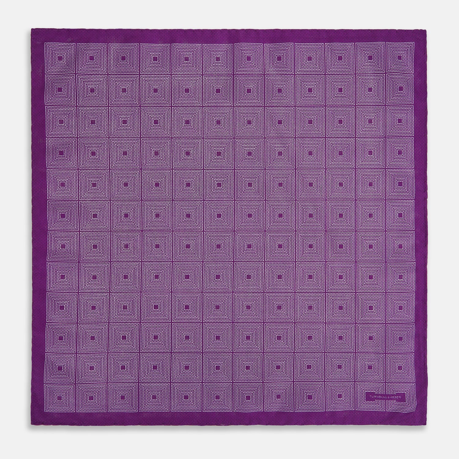 View 5 of product The Turnbull & Asser UK Geometric Purple Tile Pocket Square in Silk features a vibrant purple hue adorned with concentric square motifs. One corner is folded to reveal its double-sided design, showcasing a contrasting black-and-white dotted underside.