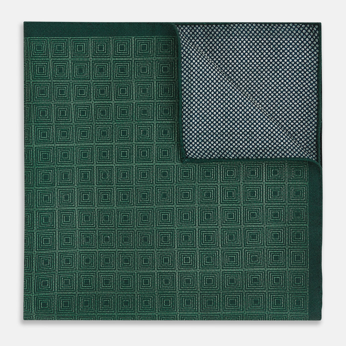 View 4 of product The Geometric Green Tile Pocket Square in Silk by Turnbull & Asser UK features a sophisticated tonal green design with a subtle pattern of concentric squares. One corner is folded to highlight the elegant double-sided construction, revealing a contrasting black and white small dot pattern on the reverse.