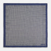 View 5 of product The Geometric Blue Pocket Square in Silk from Turnbull & Asser UK showcases a blue border and double-sided design, with a geometric pattern at the center. A folded corner reveals a refined, tighter dot motif on the reverse side, emphasizing the intricate craftsmanship of this finely woven accessory.
