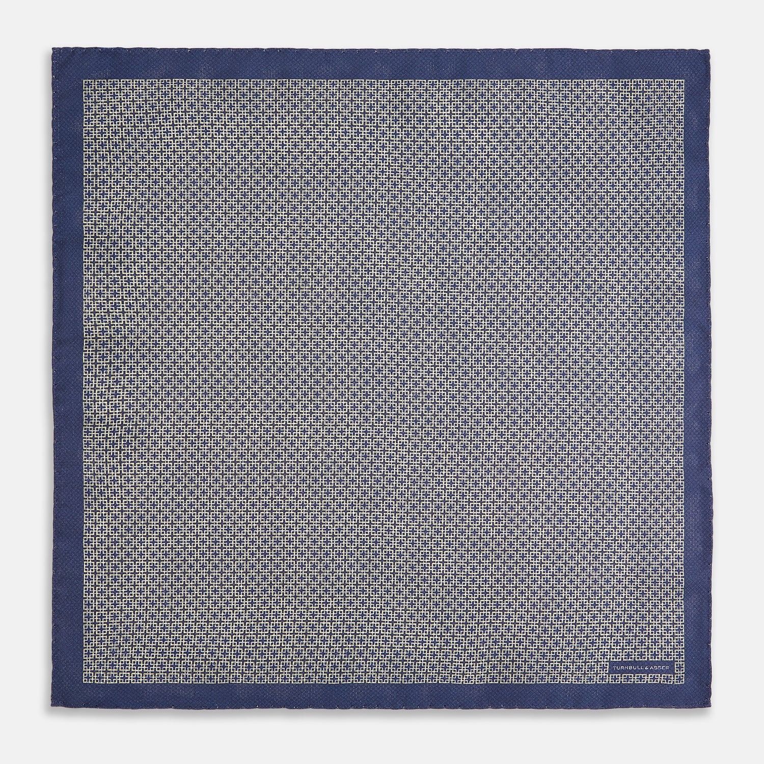 View 5 of product The Geometric Blue Pocket Square in Silk from Turnbull & Asser UK showcases a blue border and double-sided design, with a geometric pattern at the center. A folded corner reveals a refined, tighter dot motif on the reverse side, emphasizing the intricate craftsmanship of this finely woven accessory.
