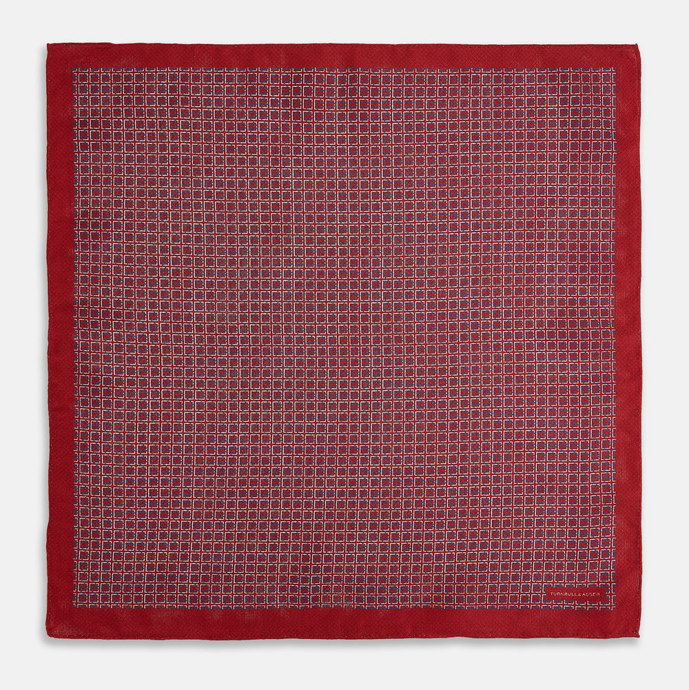 Turnbull & Asser UK’s Geometric Red Pocket Square in Silk features a small white checkered pattern and a cleverly flipped corner to showcase its contrasting black and white micro-dot reverse design.