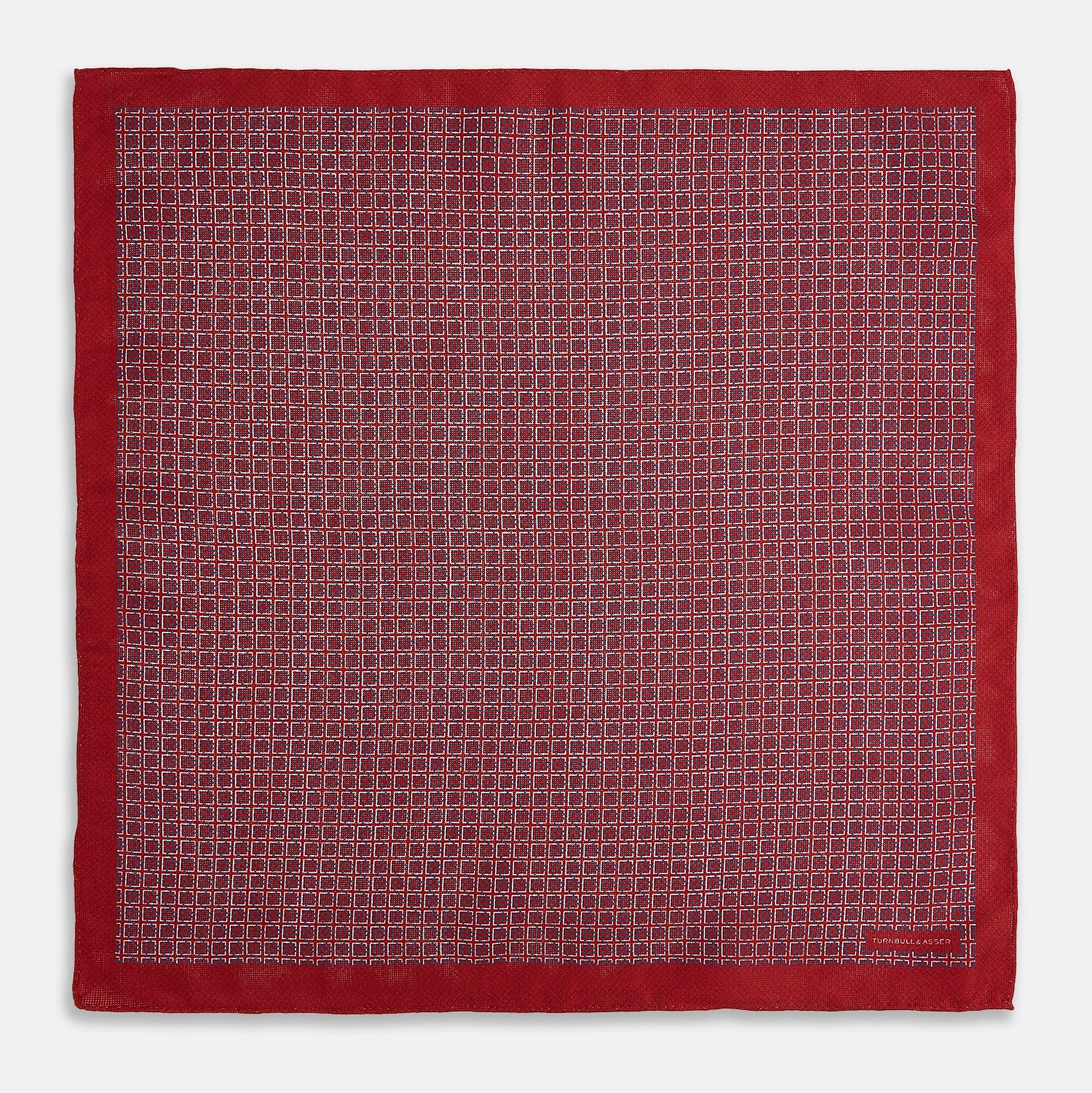 View 5 of product Turnbull & Asser UK’s Geometric Red Pocket Square in Silk features a small white checkered pattern and a cleverly flipped corner to showcase its contrasting black and white micro-dot reverse design.