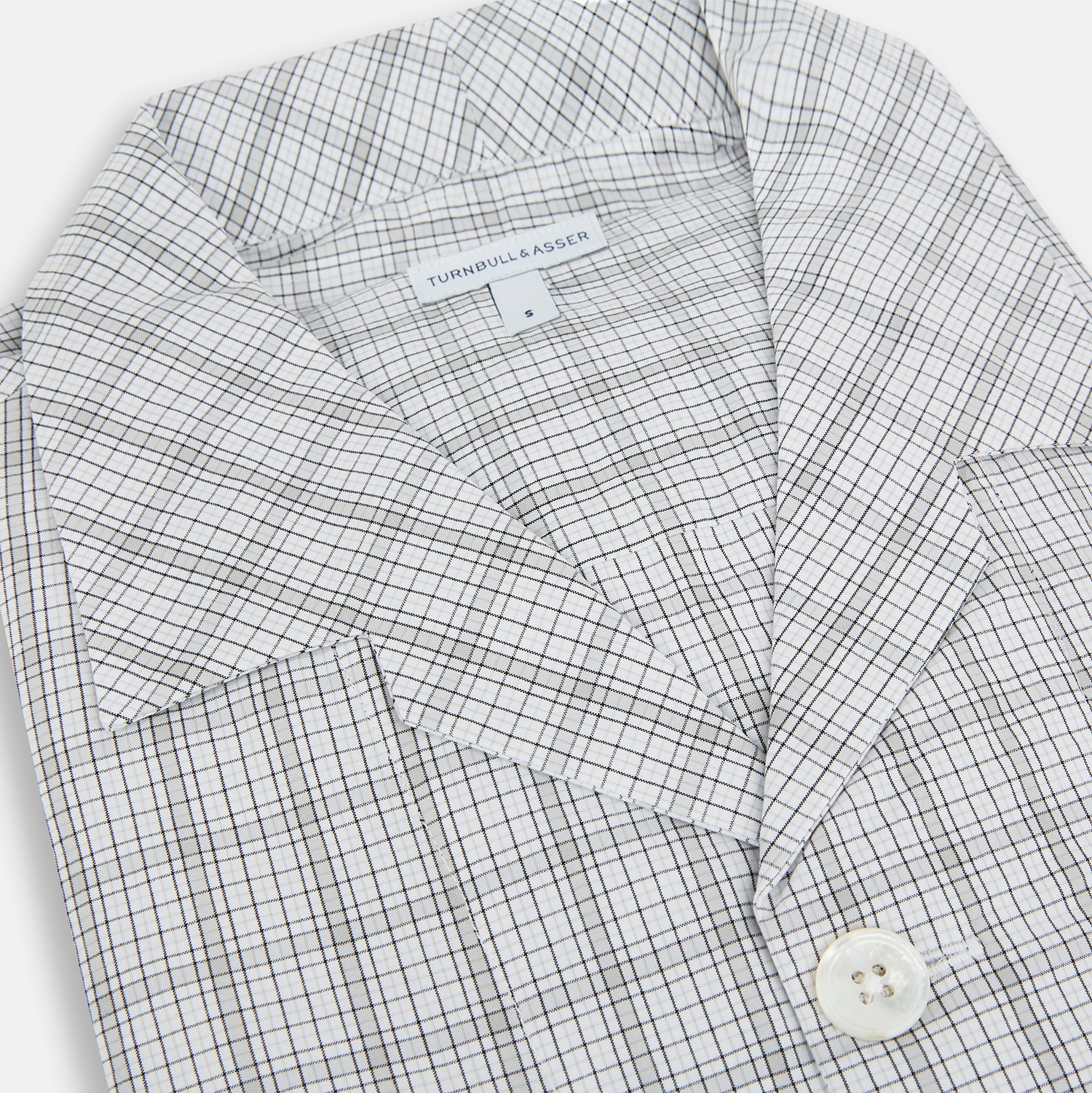 View 2 of product The Turnbull & Asser Grey Fine Multi Graph Check Pyjama Shirt features light grey and white checks, a single chest pocket, and long sleeves—ideal for stylish nightwear or as a classic pyjama shirt. Shown on a white background.
