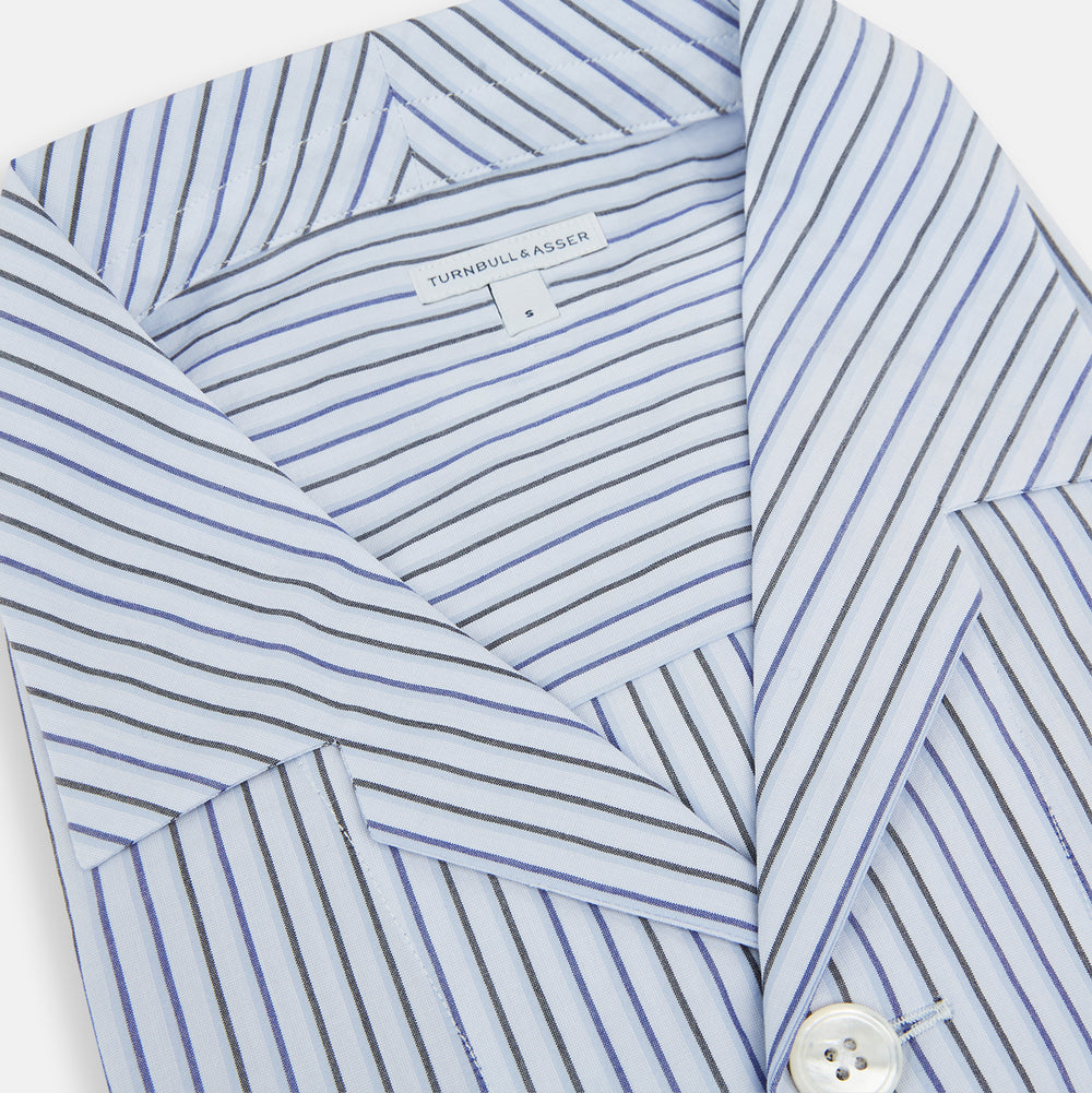 The Turnbull & Asser Blue Shadow Pinstripe Pyjama Shirt features blue and white vertical stripes, a chest pocket, and long sleeves—ideal for elegant homewear, shown against a white background.