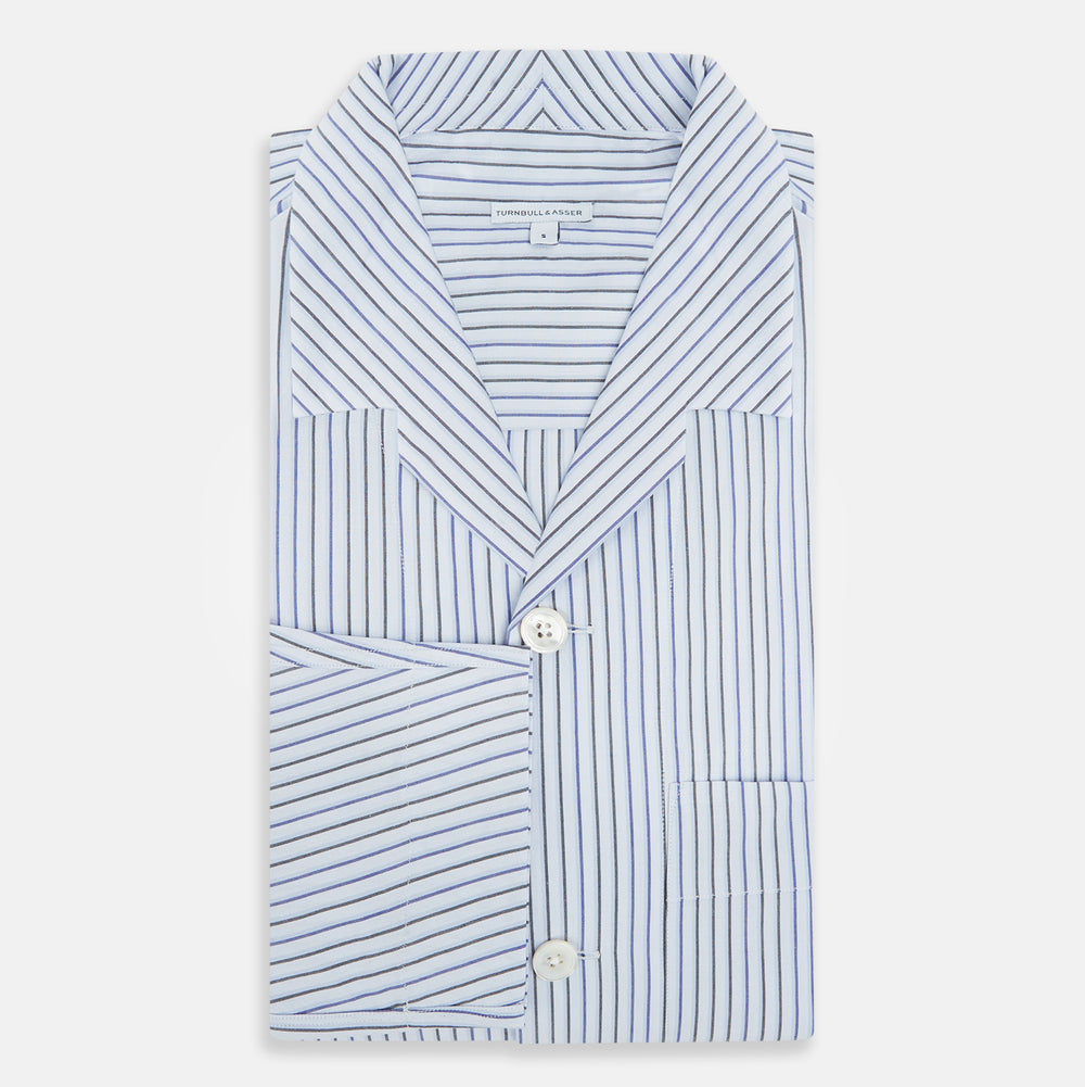 The Turnbull & Asser Blue Shadow Pinstripe Pyjama Shirt features blue and white vertical stripes, a chest pocket, and long sleeves—ideal for elegant homewear, shown against a white background.