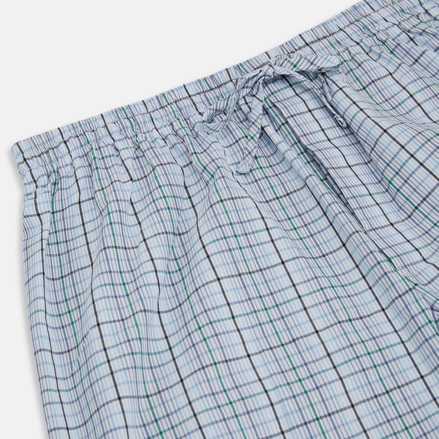 View 2 of product Turnbull & Asser’s Blue and Green Multi Track Check Pyjama Trousers feature an elastic waistband with drawstring and a blue-green check pattern on a white background, shown laid flat on a white surface.