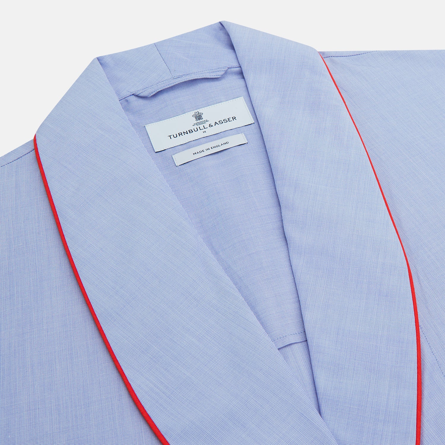 View 2 of product The Turnbull & Asser Light Blue Piped End-On-End Cotton Gown features a belted waist, three front pockets, and red piping on the collar, pockets, and cuffs—ideal for travel. Displayed against a white background.