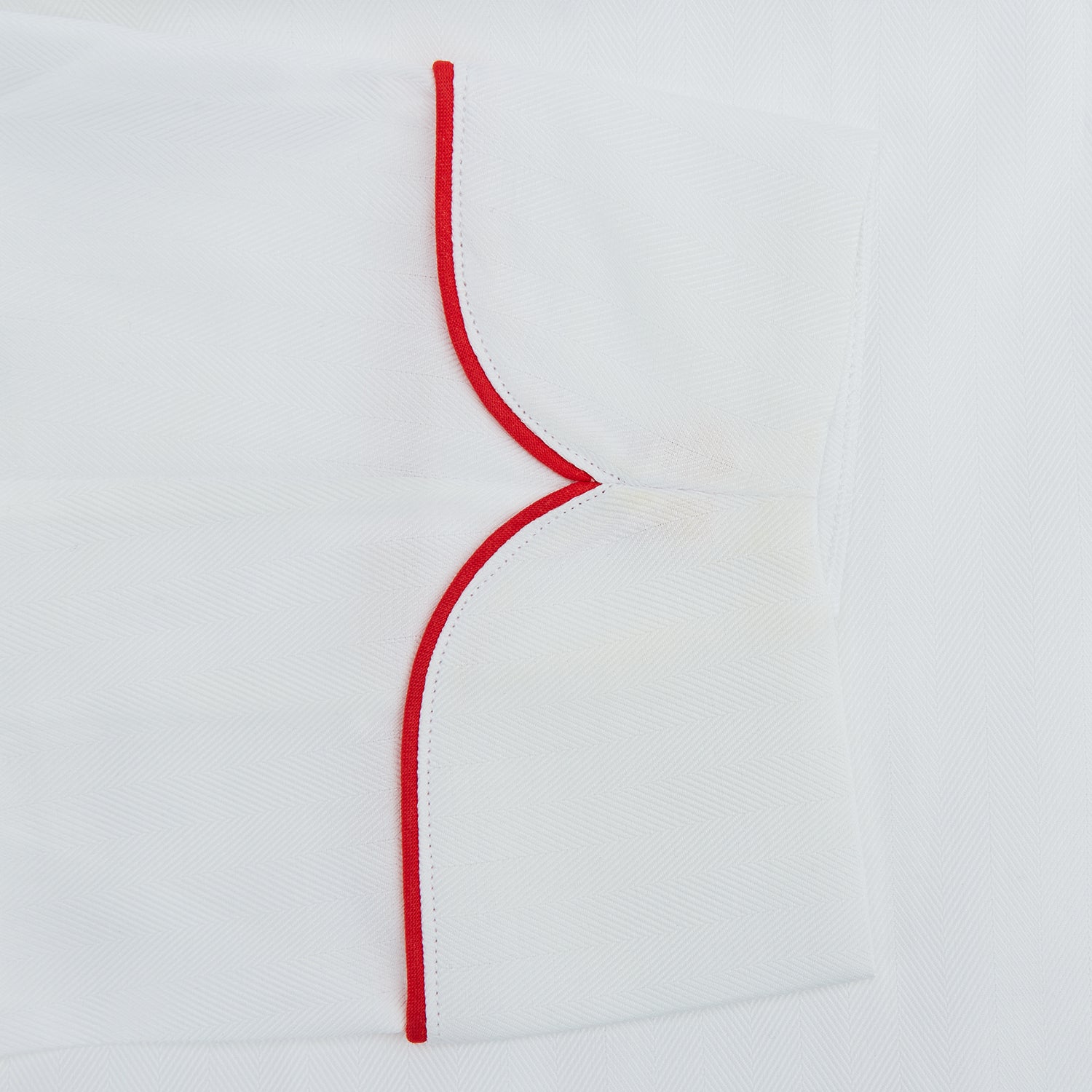View 3 of product The Turnbull & Asser White Piped Herringbone Cotton Gown features long sleeves, a waist tie, chest pocket, and striking red piping on the collar, cuffs, pocket, and edges—an elegant piece showcased against a white background.