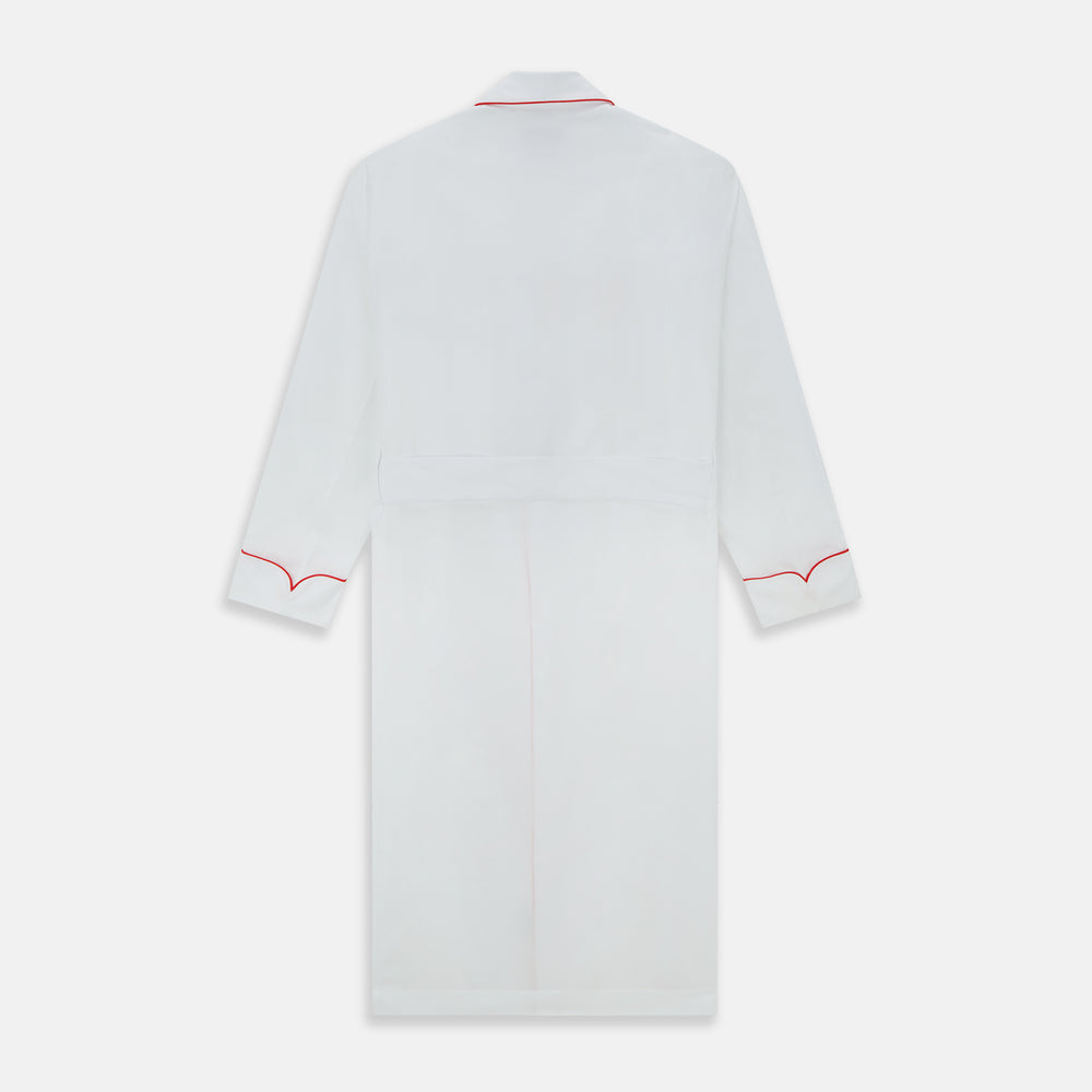 The Turnbull & Asser White Piped Herringbone Cotton Gown features long sleeves, a waist tie, chest pocket, and striking red piping on the collar, cuffs, pocket, and edges—an elegant piece showcased against a white background.