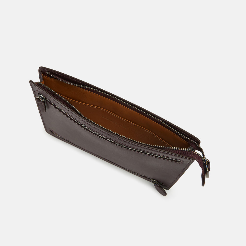 The Turnbull & Asser UK Burgundy Leather Zip Envelope Pouch features two horizontal zipper compartments with matching leather pulls, making it a stylish travel accessory or passport holder.