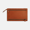 View 1 of product The Cognac Leather Zip Envelope Pouch by Turnbull & Asser UK features two horizontal zippered pockets, stitched edges, and leather pulls—offering a stylish way to organize essentials when you travel.