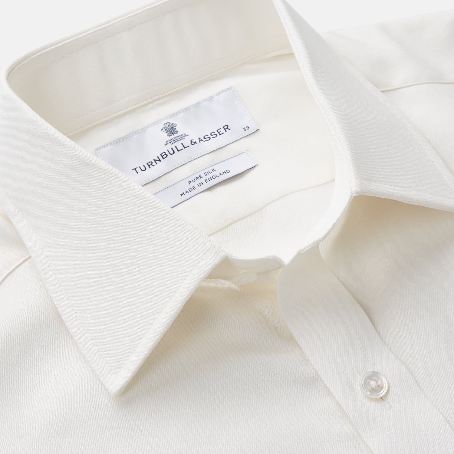 View 2 of product The Turnbull & Asser Cream Silk Mayfair Shirt features long sleeves, a classic collar, button-down front, and buttoned cuffs, shown laid flat on a white background.