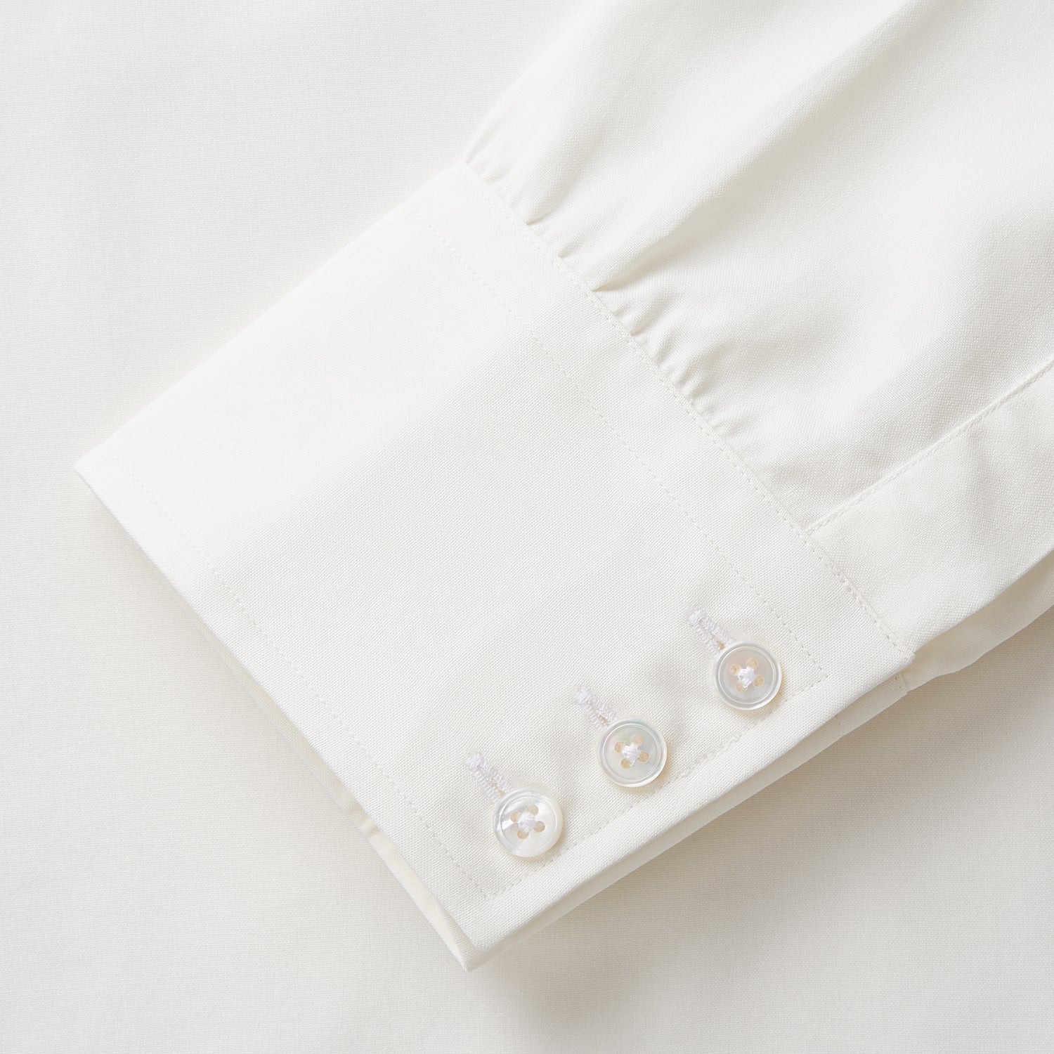 View 3 of product The Turnbull & Asser Cream Silk Mayfair Shirt features long sleeves, a classic collar, button-down front, and buttoned cuffs, shown laid flat on a white background.