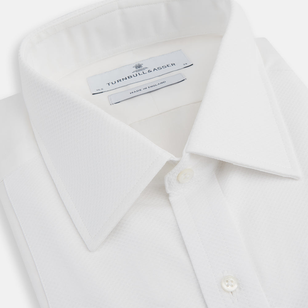 The Turnbull & Asser White Marcella Dress Shirt features a T&A collar, double cuffs, a classic bib front, and a button-down design—ideal for formal occasions. Displayed against a plain white background.