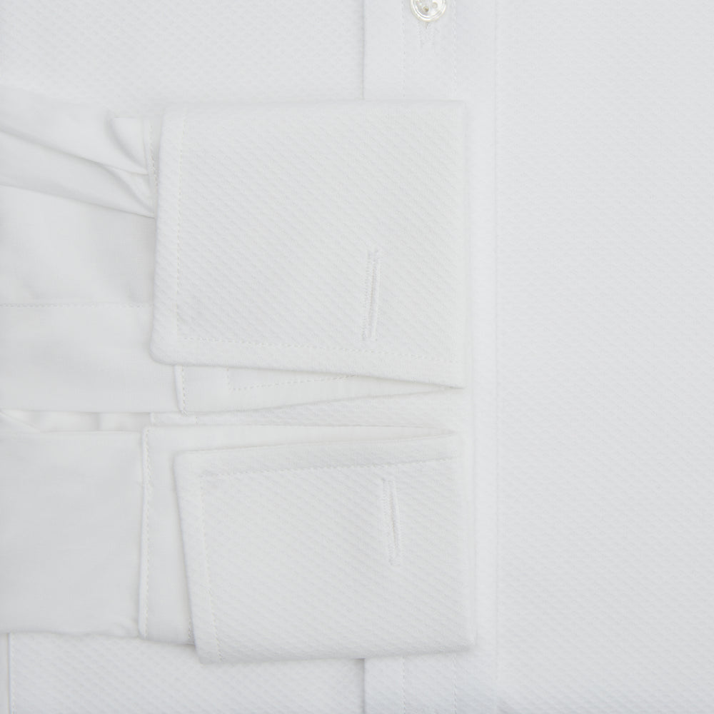 The Turnbull & Asser White Marcella Dress Shirt features a T&A collar, double cuffs, a classic bib front, and a button-down design—ideal for formal occasions. Displayed against a plain white background.