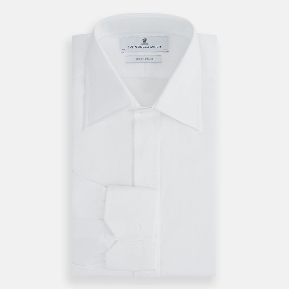 The Turnbull & Asser Casino Royale White Dress Shirt, as seen on James Bond, features long sleeves, a button-down front, and classic collar and cuffs. Displayed against a plain white background.