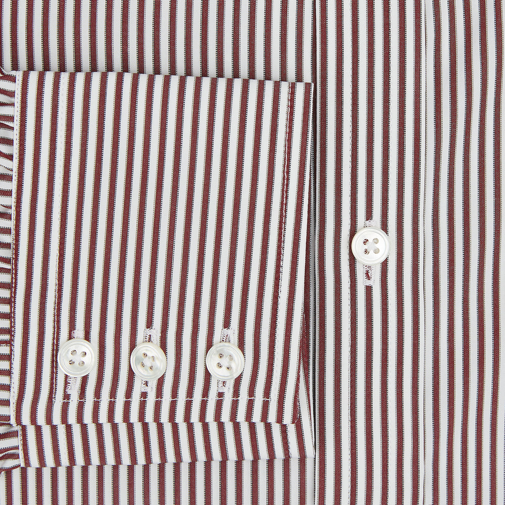 The Turnbull & Asser Burgundy Halo Stripe Winston Shirt features long sleeves, a classic T&A collar, buttoned cuffs, narrow vertical burgundy and white stripes, and is crafted from organic cotton. Displayed on a white background.