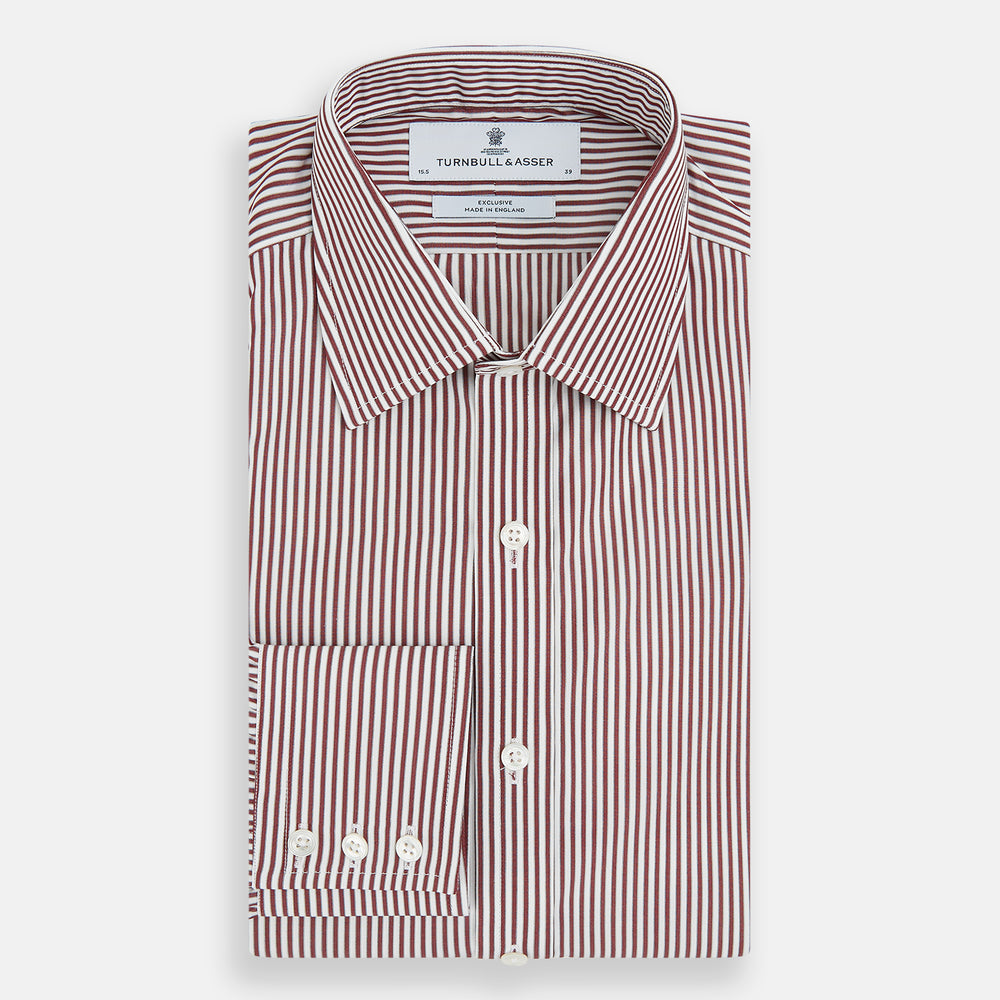 The Turnbull & Asser Burgundy Halo Stripe Winston Shirt features long sleeves, a classic T&A collar, buttoned cuffs, narrow vertical burgundy and white stripes, and is crafted from organic cotton. Displayed on a white background.