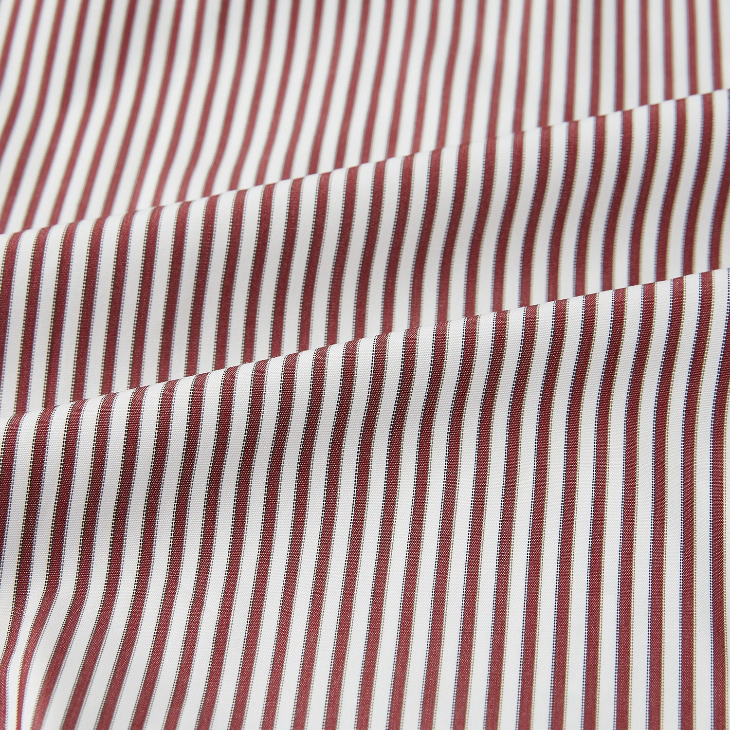 View 6 of product The Turnbull & Asser Burgundy Halo Stripe Winston Shirt features long sleeves, a classic T&A collar, buttoned cuffs, narrow vertical burgundy and white stripes, and is crafted from organic cotton. Displayed on a white background.