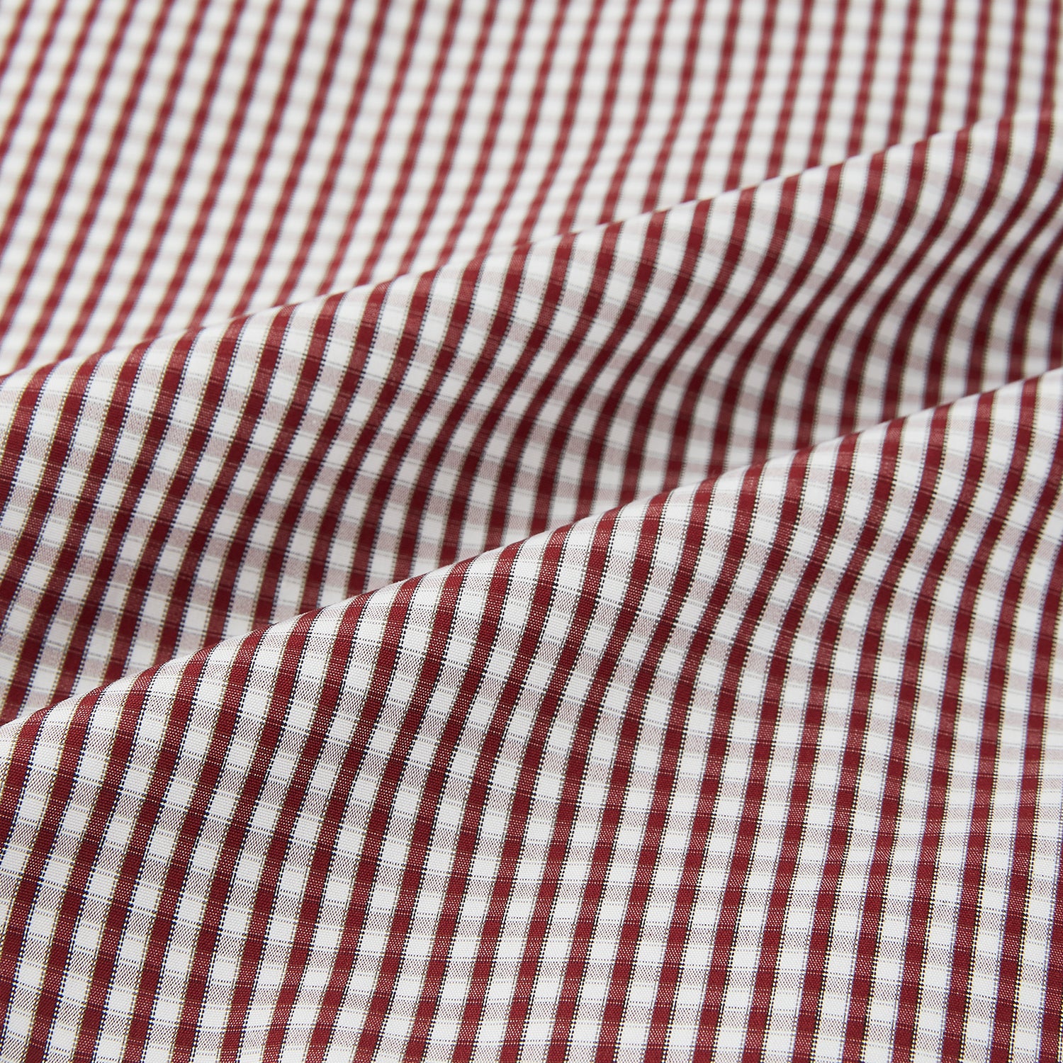 View 6 of product The Turnbull & Asser Burgundy Micro Check Winston Shirt is a long-sleeved, button-up Mayfair fit dress shirt with a collar and buttoned cuffs, featuring a small red and white check pattern and shown on a white background.
