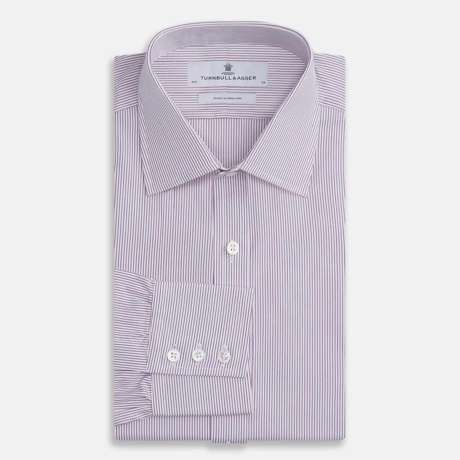 View 4 of product The Purple Pinstripe Mayfair Shirt by Turnbull & Asser is a light purple cotton poplin long-sleeve button-up with white stripes, a pointed collar, white buttons, and cuffed sleeves, shown laid flat on a white background.