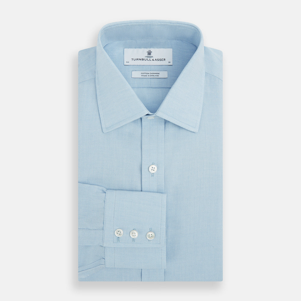 The Turnbull & Asser Blue Cotton Cashmere Mayfair Shirt features long sleeves, a classic collar, buttoned cuffs, and white buttons, shown against a white background.