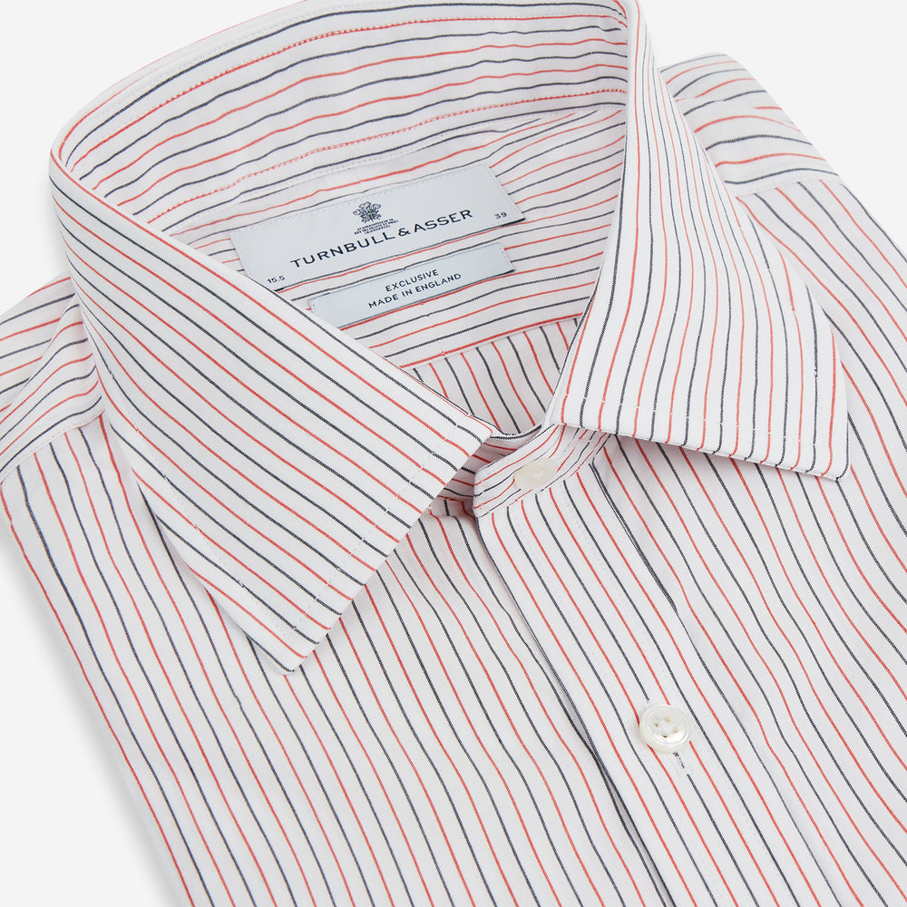 The Turnbull & Asser Red and Navy Pinstripe Mayfair Shirt, an organic cotton long-sleeve button-up with a collar, features thin vertical red and navy pinstripes on white, shown laid flat on a white surface.