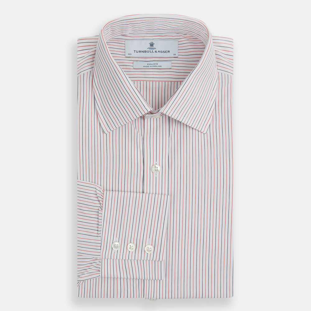 The Turnbull & Asser Red and Navy Pinstripe Mayfair Shirt, an organic cotton long-sleeve button-up with a collar, features thin vertical red and navy pinstripes on white, shown laid flat on a white surface.