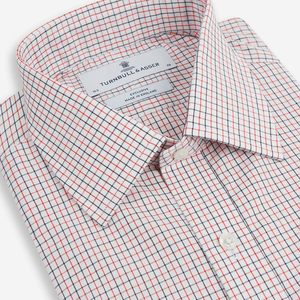 The Turnbull & Asser Red and Navy Graph Check Mayfair Shirt is a long-sleeved organic cotton button-up featuring a collar, buttoned cuffs, and a small red and navy check pattern, shown against a plain white background.