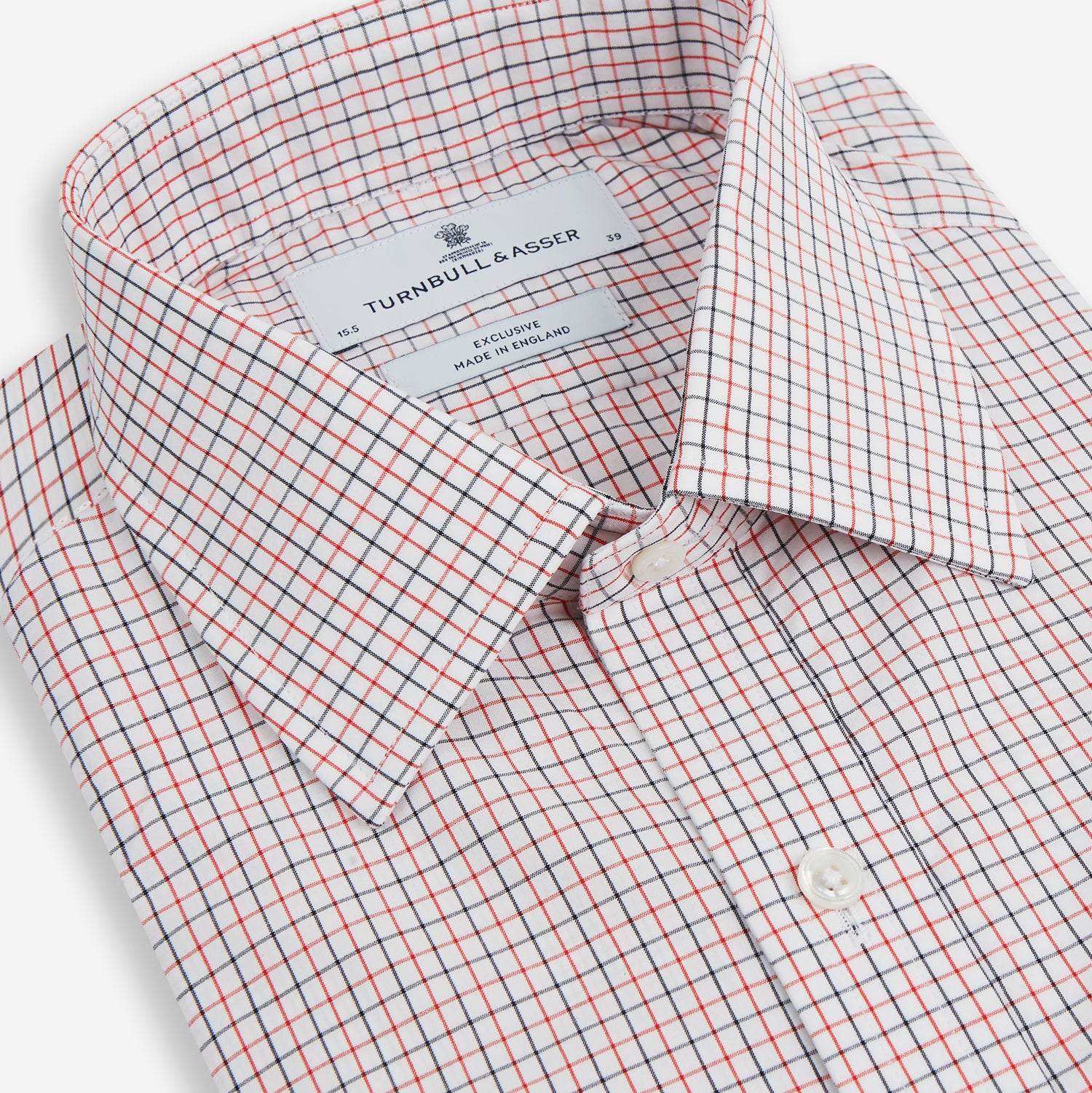 View 2 of product The Turnbull & Asser Red and Navy Graph Check Mayfair Shirt is a long-sleeved organic cotton button-up featuring a collar, buttoned cuffs, and a small red and navy check pattern, shown against a plain white background.