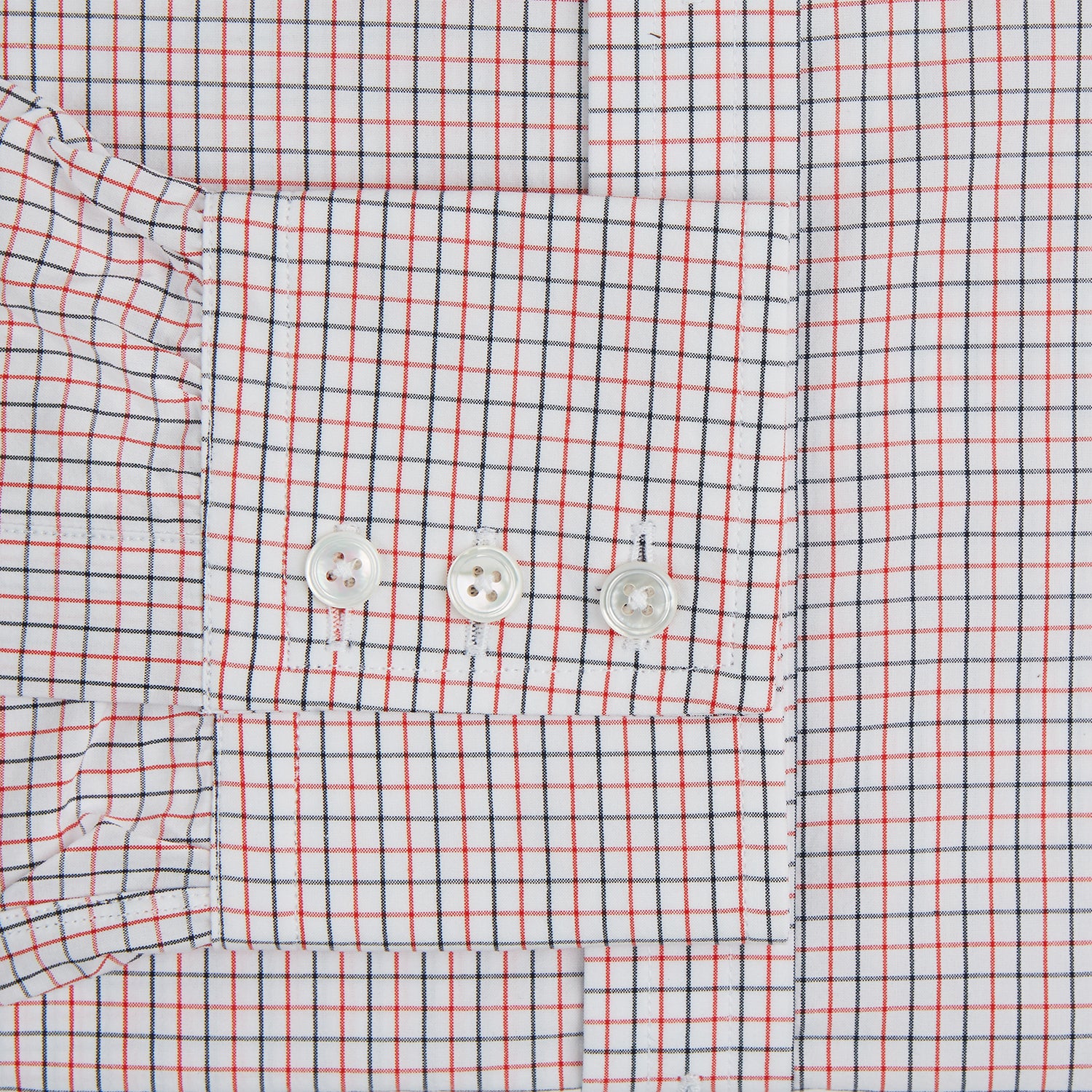 View 3 of product The Turnbull & Asser Red and Navy Graph Check Mayfair Shirt is a long-sleeved organic cotton button-up featuring a collar, buttoned cuffs, and a small red and navy check pattern, shown against a plain white background.