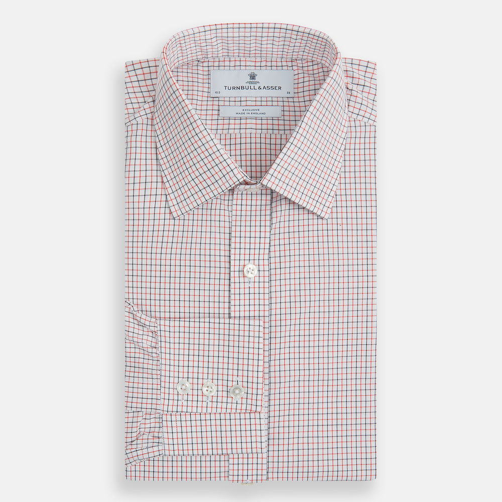 The Turnbull & Asser Red and Navy Graph Check Mayfair Shirt is a long-sleeved organic cotton button-up featuring a collar, buttoned cuffs, and a small red and navy check pattern, shown against a plain white background.