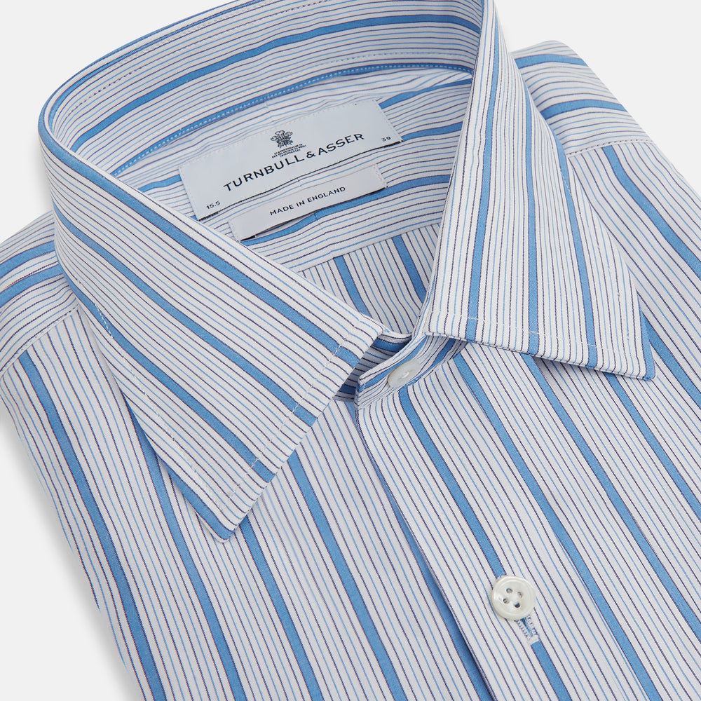 The Turnbull & Asser Blue Multi Track Stripe Mayfair Shirt is a button-up, long-sleeve shirt in white organic cotton with blue vertical stripes, classic collar, and buttoned cuffs.