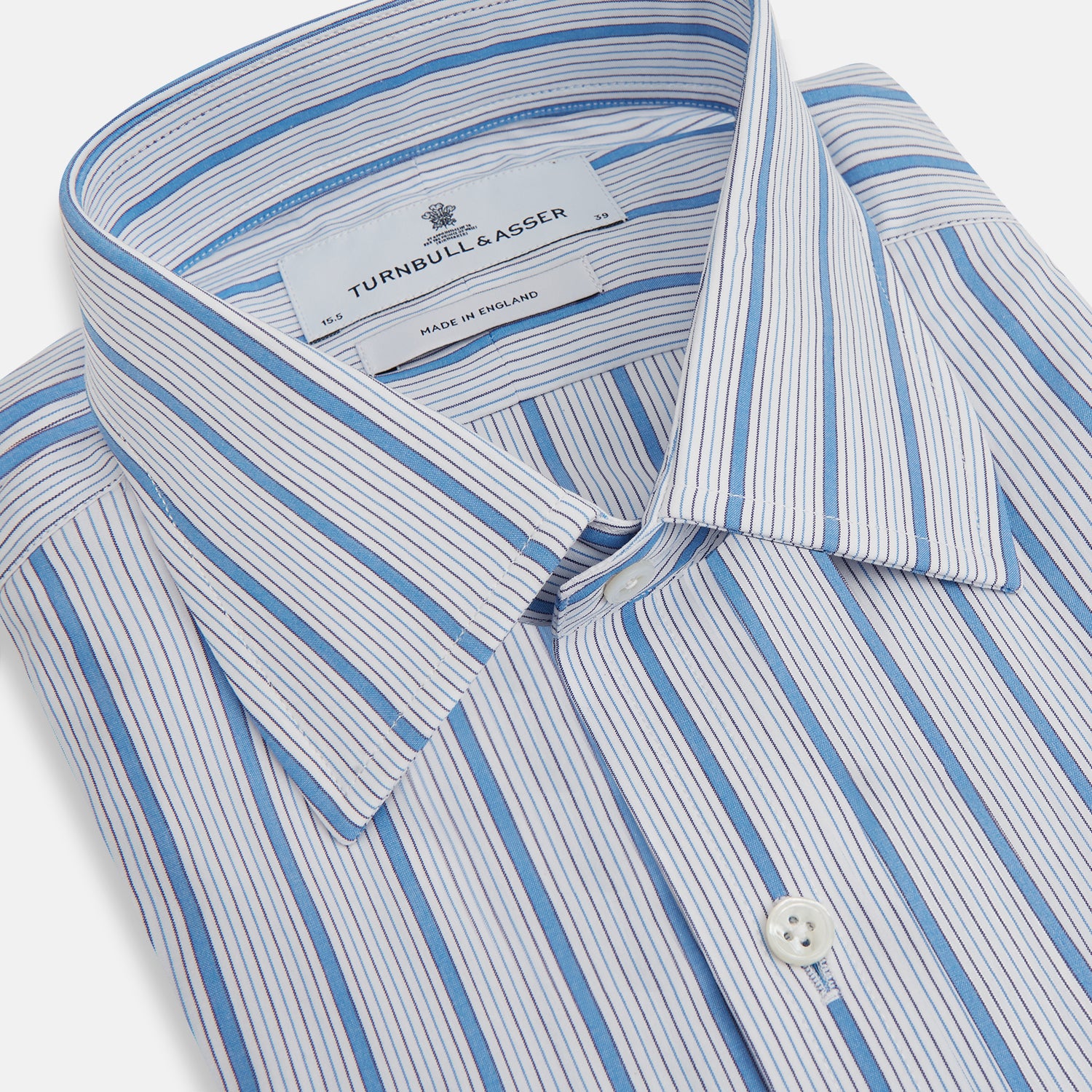View 2 of product The Turnbull & Asser Blue Multi Track Stripe Mayfair Shirt is a button-up, long-sleeve shirt in white organic cotton with blue vertical stripes, classic collar, and buttoned cuffs.