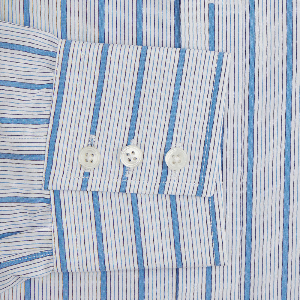 The Turnbull & Asser Blue Multi Track Stripe Mayfair Shirt is a button-up, long-sleeve shirt in white organic cotton with blue vertical stripes, classic collar, and buttoned cuffs.