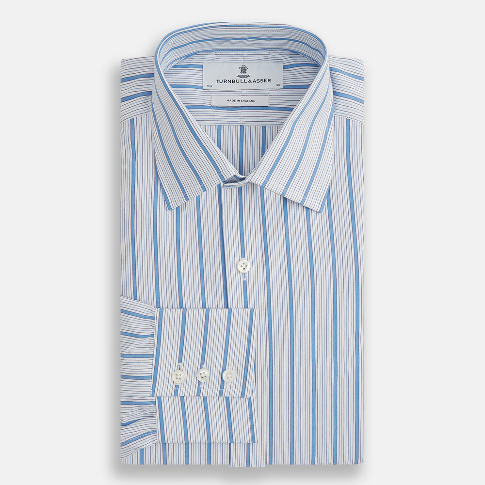 The Turnbull & Asser Blue Multi Track Stripe Mayfair Shirt is a button-up, long-sleeve shirt in white organic cotton with blue vertical stripes, classic collar, and buttoned cuffs.