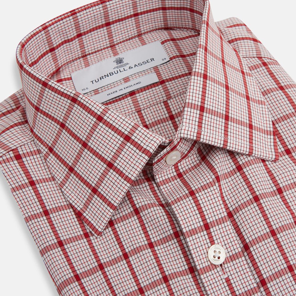 The Red Graph Overlay Check Mayfair Shirt by Turnbull & Asser is a long-sleeved, button-up shirt with a white base and red check pattern, featuring a collar and buttoned cuffs. Displayed on a plain white background.