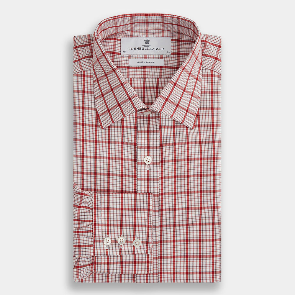 The Red Graph Overlay Check Mayfair Shirt by Turnbull & Asser is a long-sleeved, button-up shirt with a white base and red check pattern, featuring a collar and buttoned cuffs. Displayed on a plain white background.