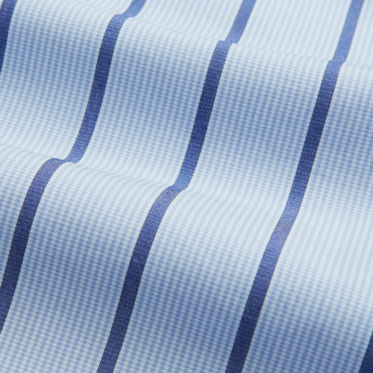 View 5 of product The Blue Track Stripe Mayfair Shirt by Turnbull & Asser features long sleeves, a T&A collar, vertical dark blue stripes on light blue organic cotton, and is shown against a plain white background.