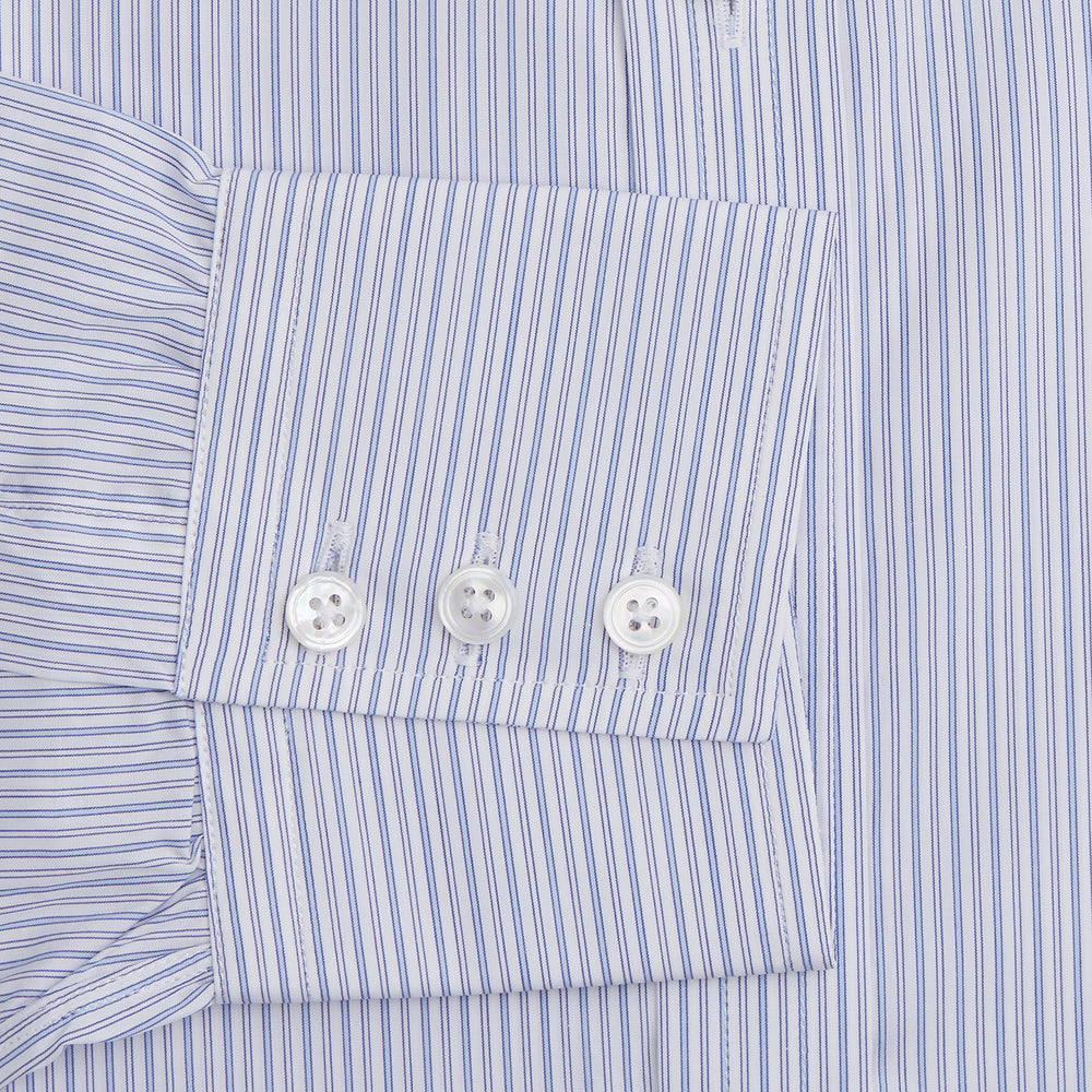 The Light Blue Track Stripe Mayfair Shirt by Turnbull & Asser is a long-sleeve button-up with thin white stripes, pointed collar, and buttoned cuffs. Expertly crafted from Egyptian cotton, it's shown laid flat on a white background.