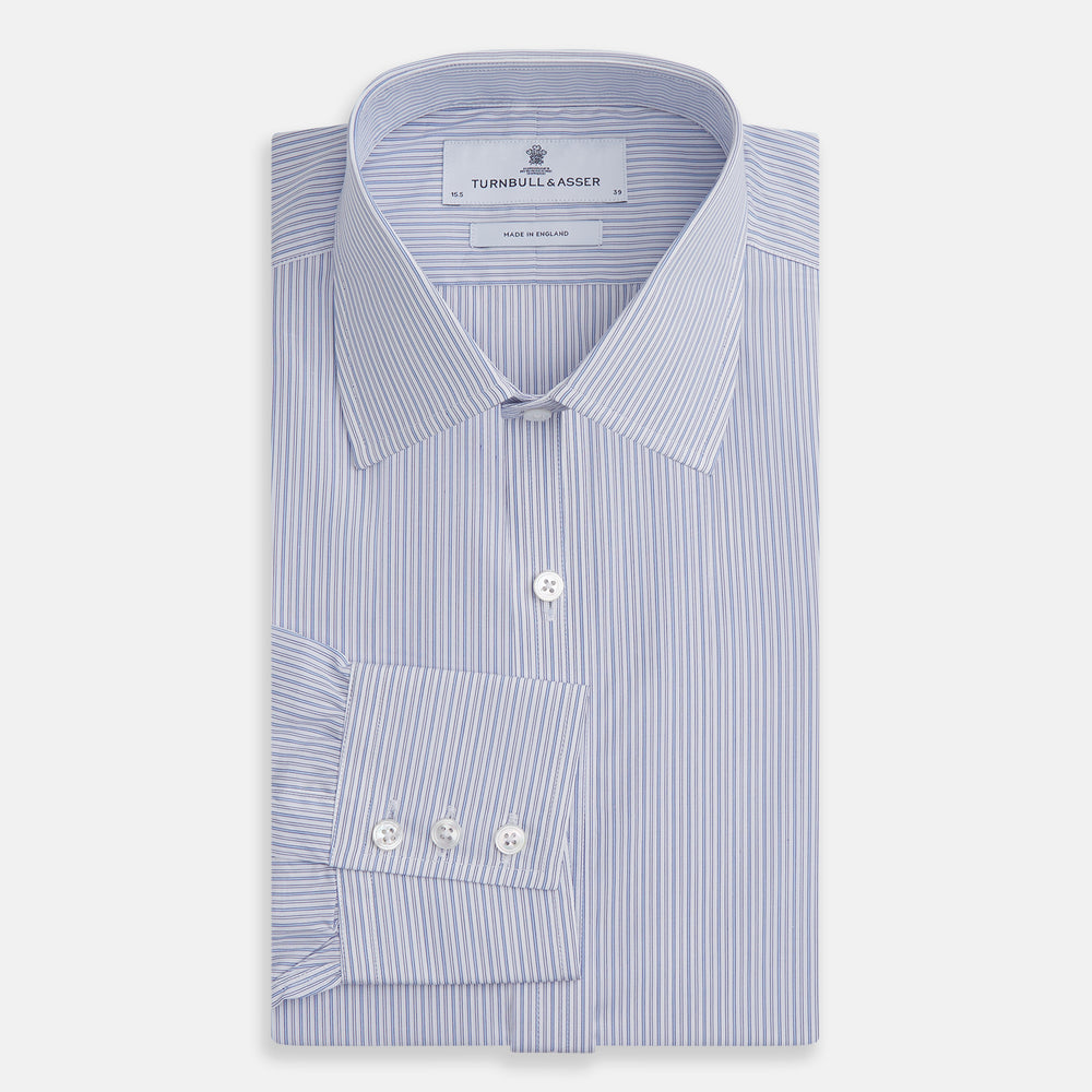 The Light Blue Track Stripe Mayfair Shirt by Turnbull & Asser is a long-sleeve button-up with thin white stripes, pointed collar, and buttoned cuffs. Expertly crafted from Egyptian cotton, it's shown laid flat on a white background.