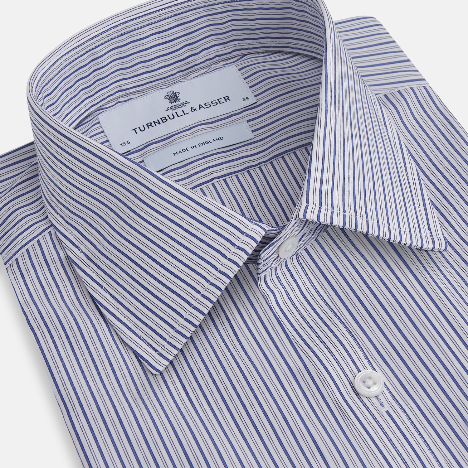 View 2 of product The Dark Blue Track Stripe Mayfair Shirt by Turnbull & Asser is a long-sleeve, button-up Egyptian cotton shirt with a classic collar and thin blue and white stripes, laid flat on a white background.