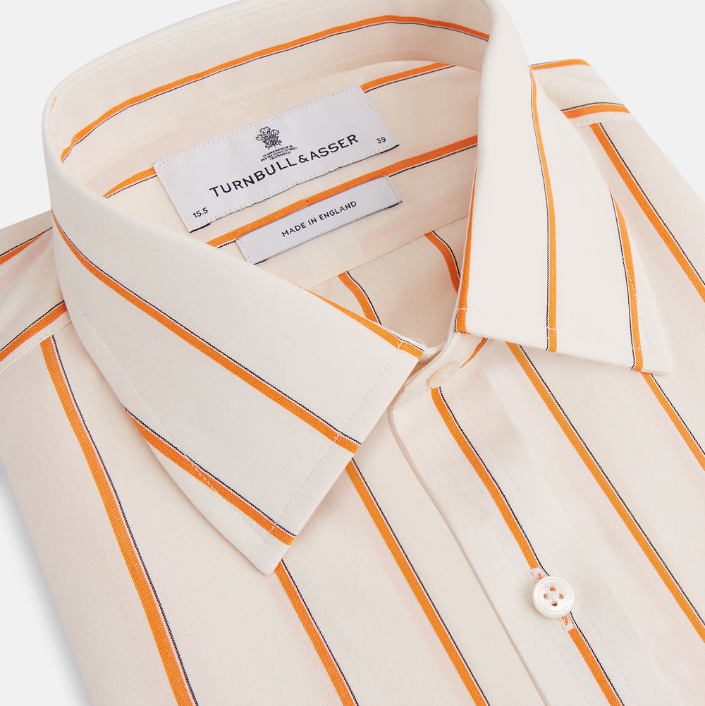 The Orange Track Stripe Mayfair Shirt by Turnbull & Asser features a white base with vertical orange stripes in breathable cotton, plus contrasting horizontal-striped collar and cuffs, shown neatly laid flat on a white background.