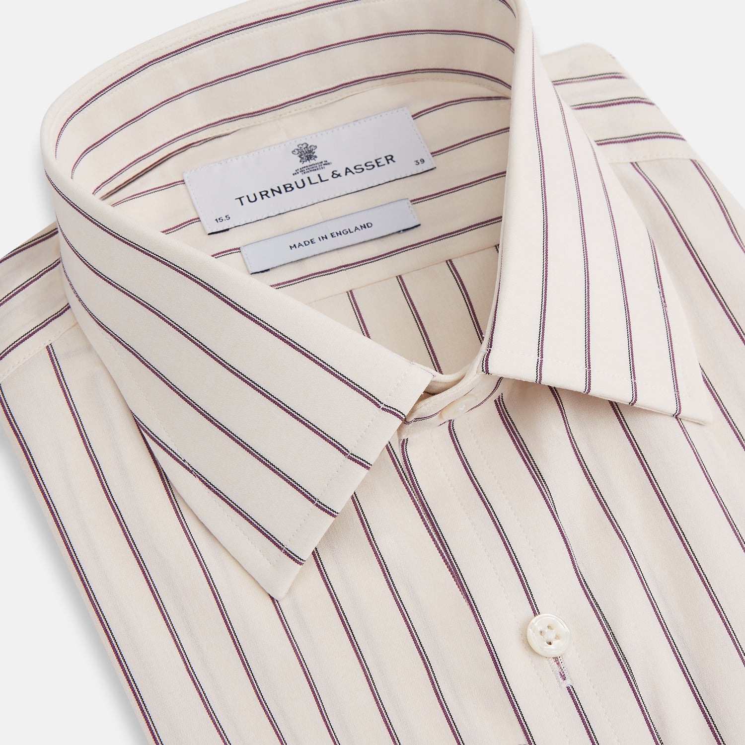 View 2 of product The Purple Halo Stripe Mayfair Shirt by Turnbull & Asser is an organic cotton, long-sleeved shirt with a T&A collar, buttoned cuffs, and thin black stripes on a white base, neatly laid flat on a white background.