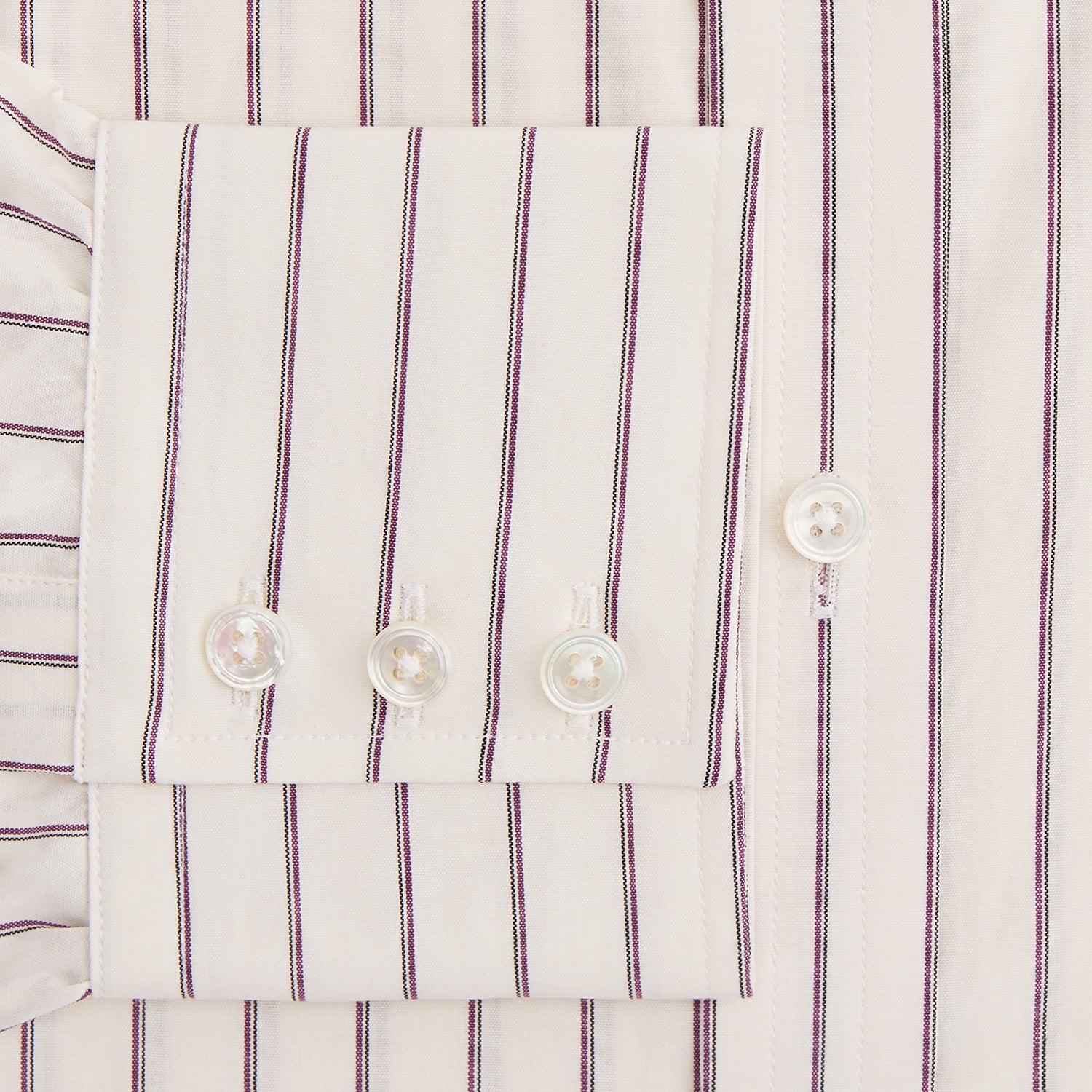 View 3 of product The Purple Halo Stripe Mayfair Shirt by Turnbull & Asser is an organic cotton, long-sleeved shirt with a T&A collar, buttoned cuffs, and thin black stripes on a white base, neatly laid flat on a white background.